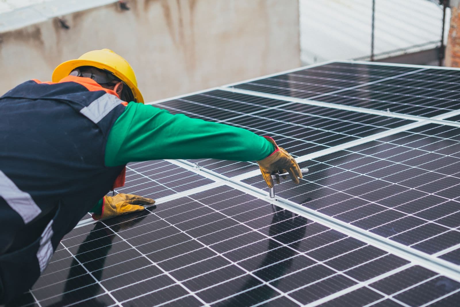 Technician in a hard hat fastening rooftop solar panels