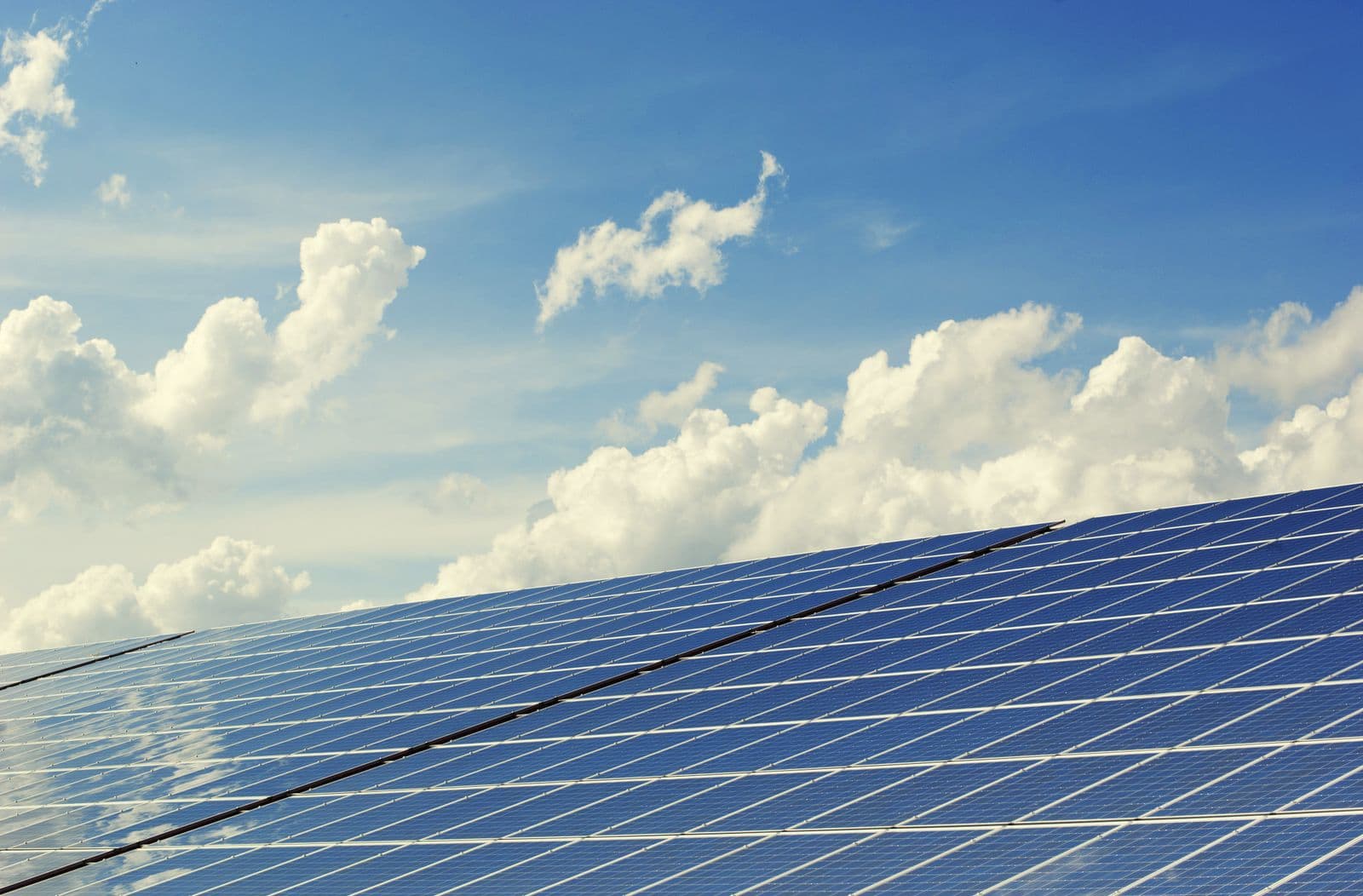 Low-angle view of blue solar panels against a bright sky