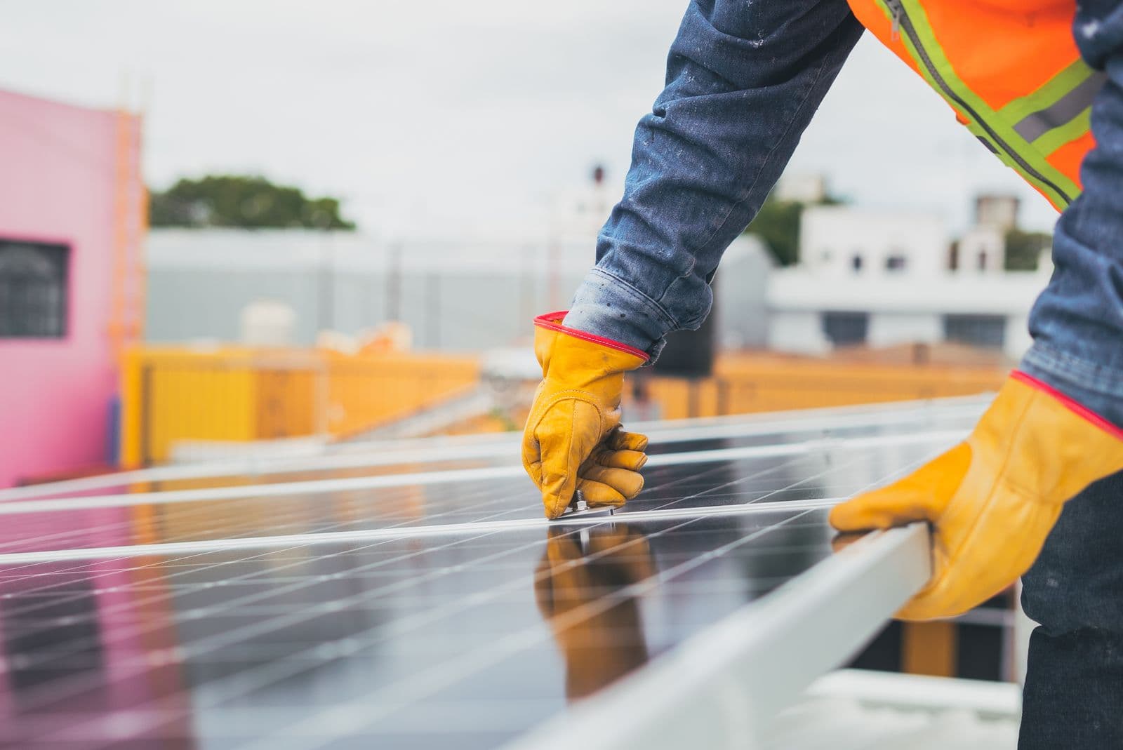 Gloved hands adjusting hardware on a rooftop solar panel